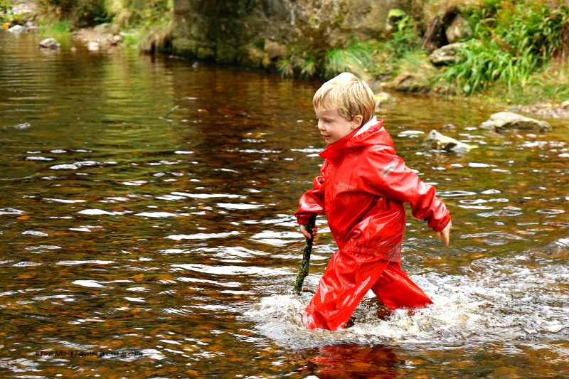 boy-red-raingear-wading-river-stick