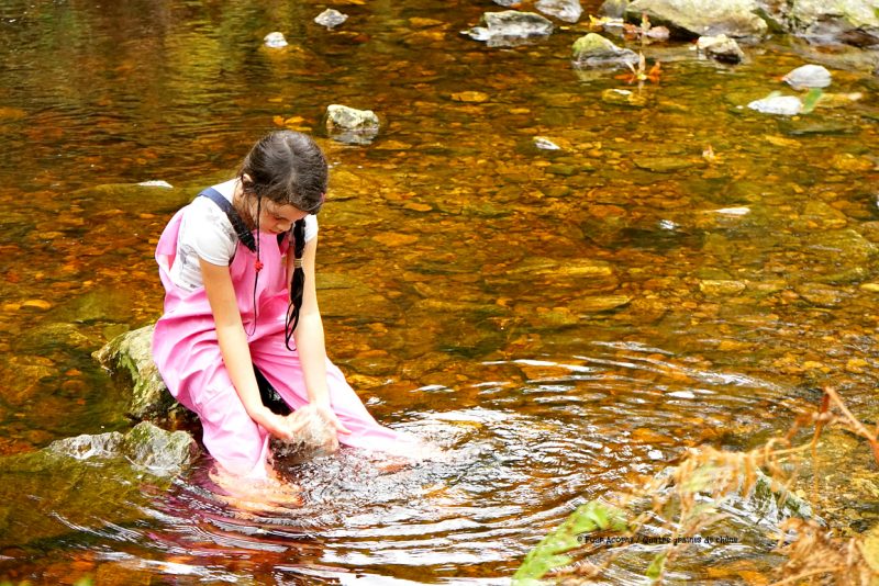 girl-pink-raingear-playing-water-river