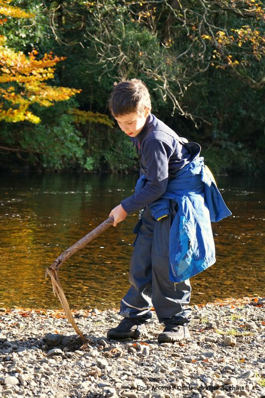 boy-stick-river-digging-pebbles-autumn-sunshine