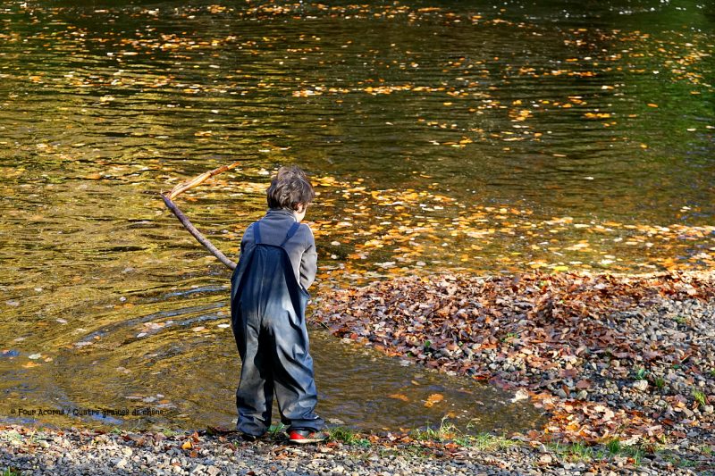 boy-stick-riverside-autumn-leaves