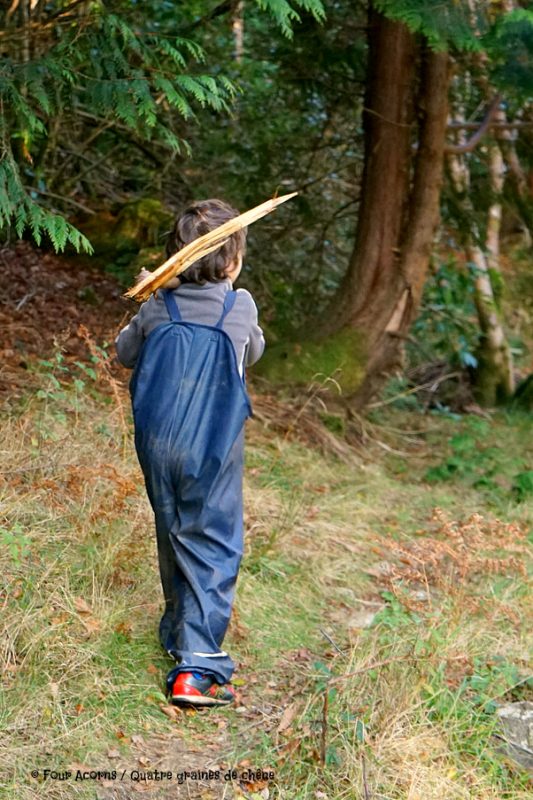 boy-carrying-stick-forest-navy-raingear