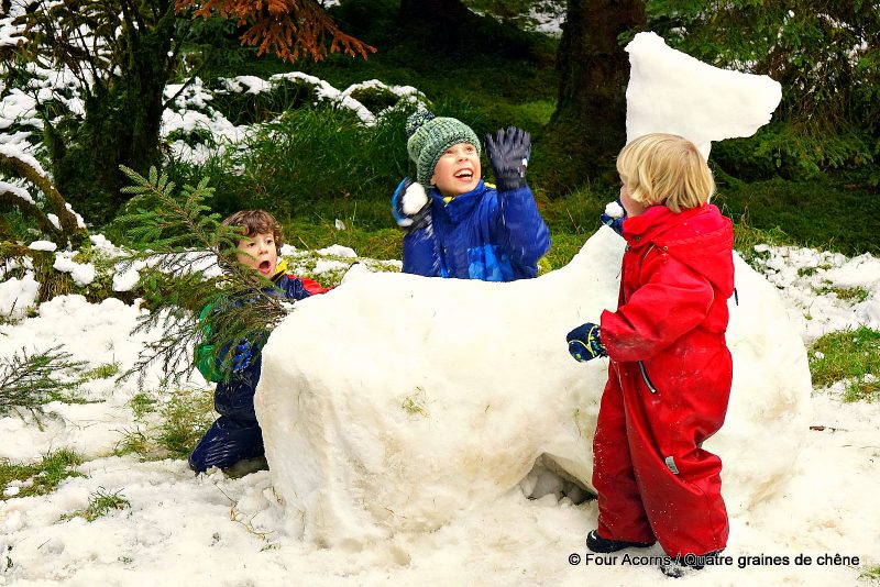 three-children-playing-beside-snow-horse-sculpture