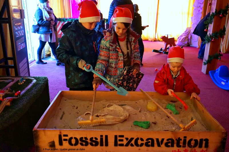 three-children-santa-hats-sandpit-fossil-excavation