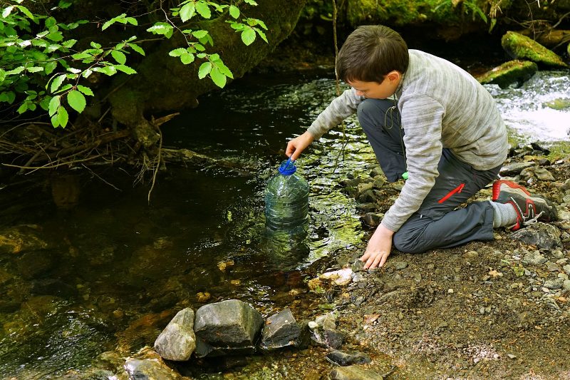 boy-fetching-water-stream-river