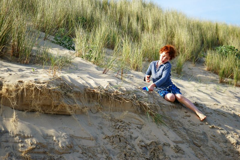 red-hair-boy-playing-sand-dune-sunshine