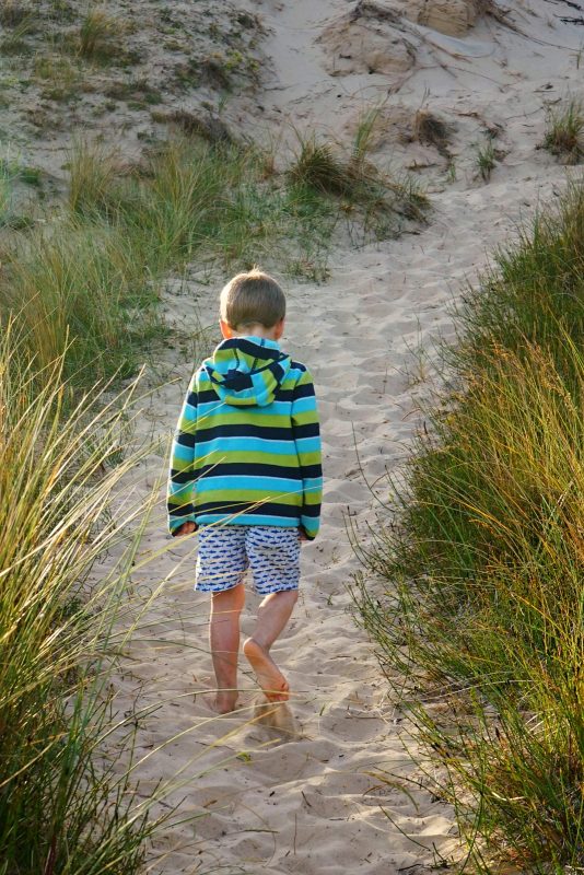 boy-walking-sand-dune-evening-light